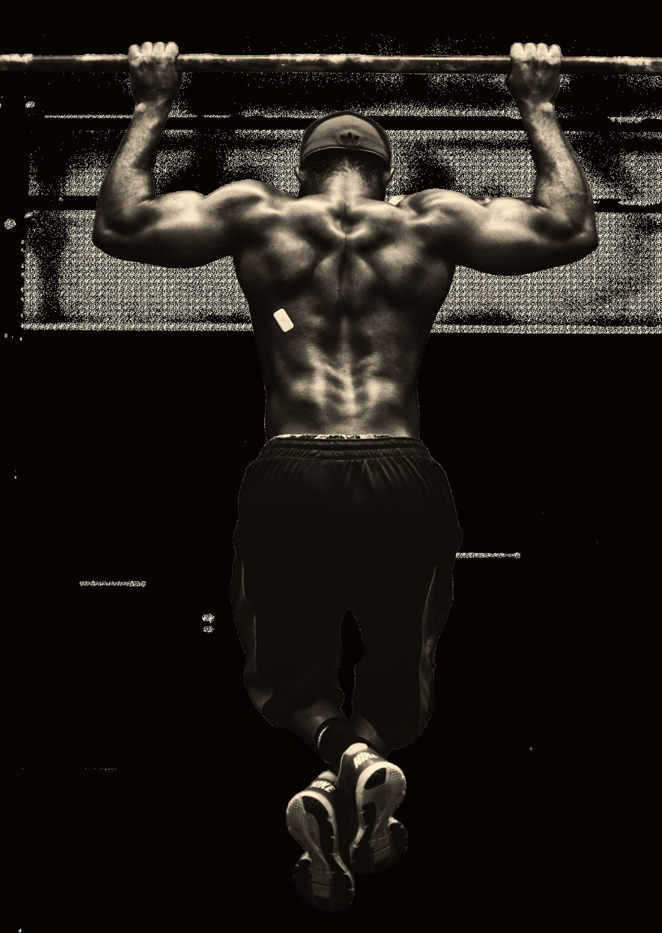 An athlete pulling up in low light with a small Z1 sensor on the working back muscle